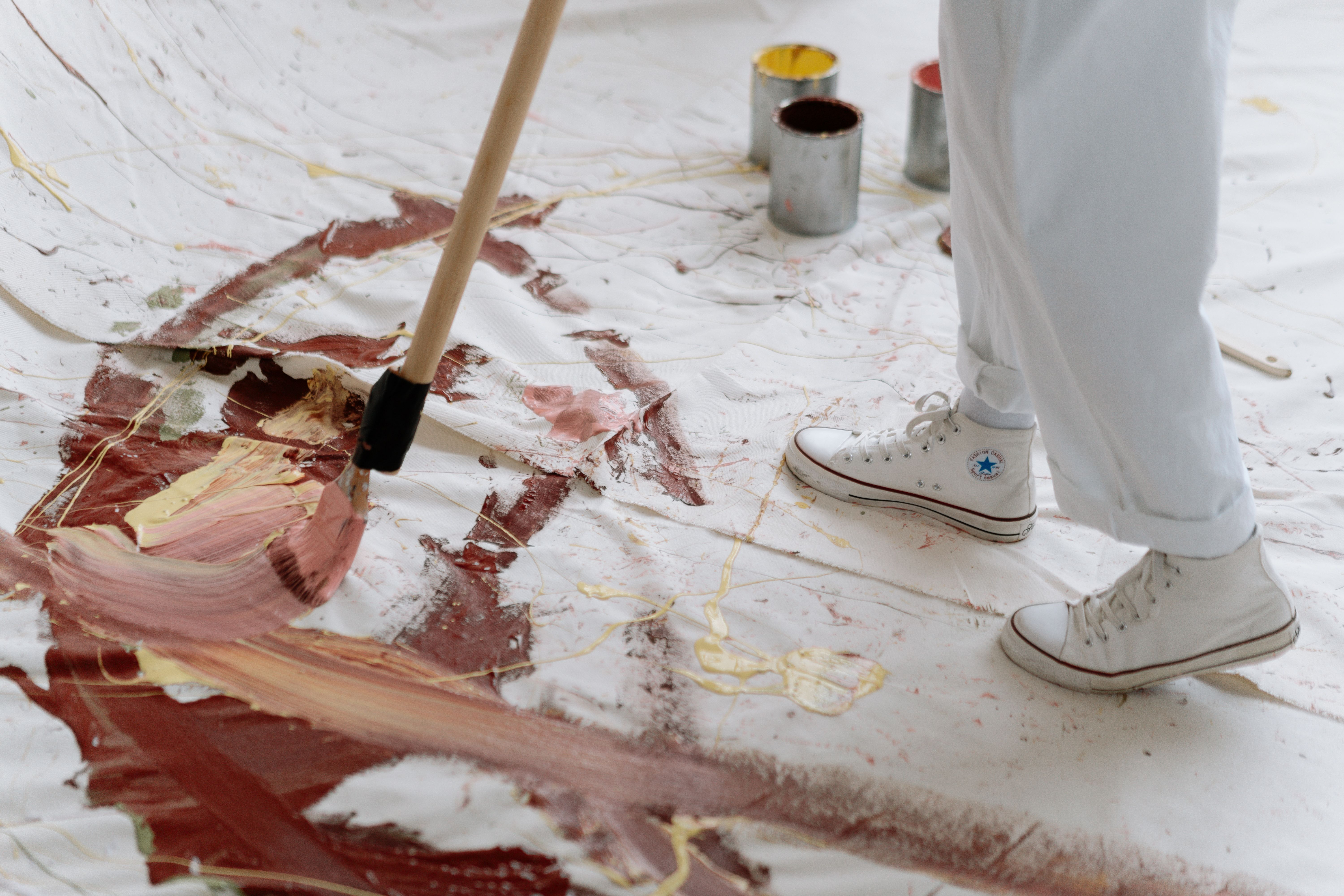 Artist using a brush to paint abstract patterns on a large canvas